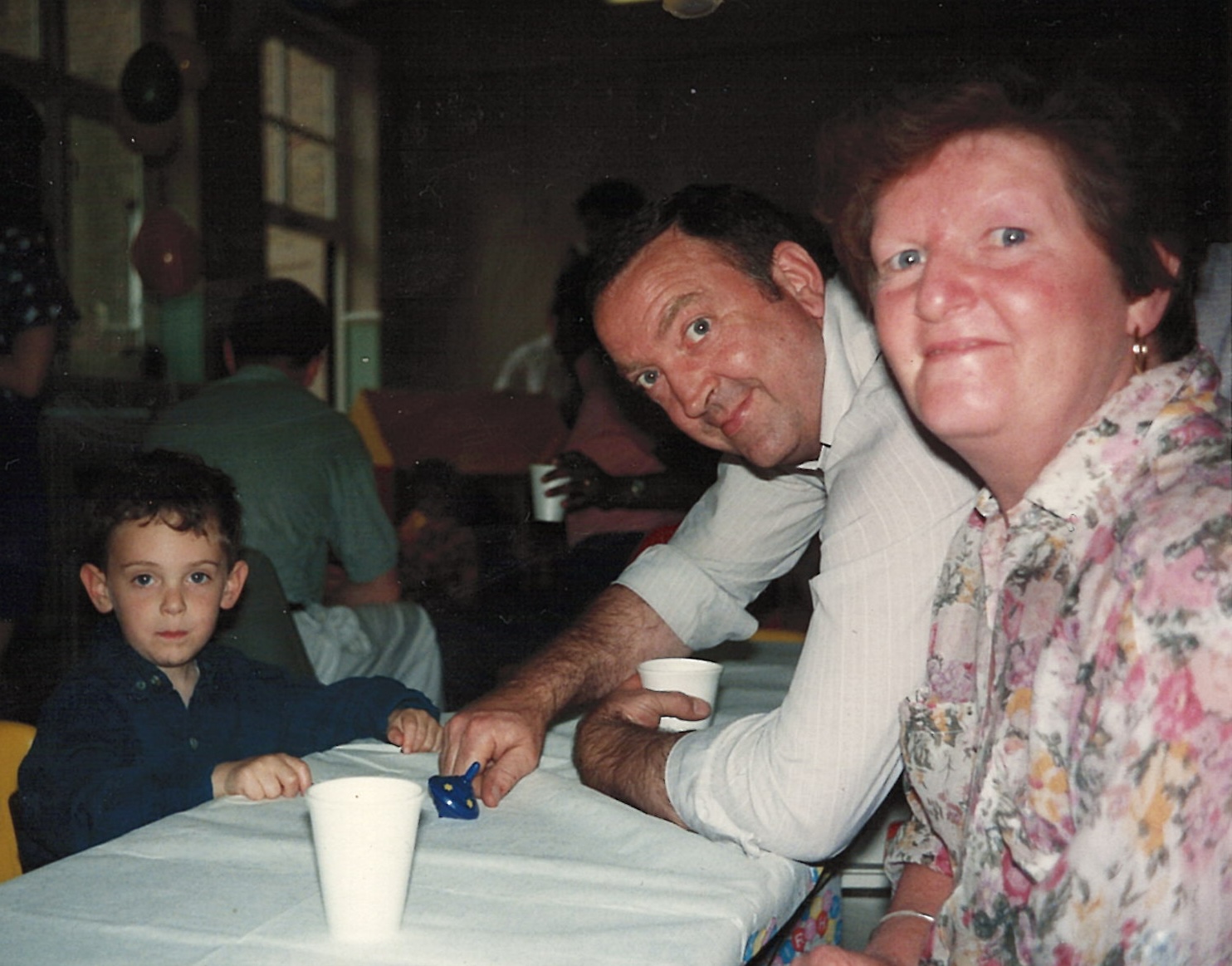 Photo of me as a child, my Nan and my Grandad sitting at a table.